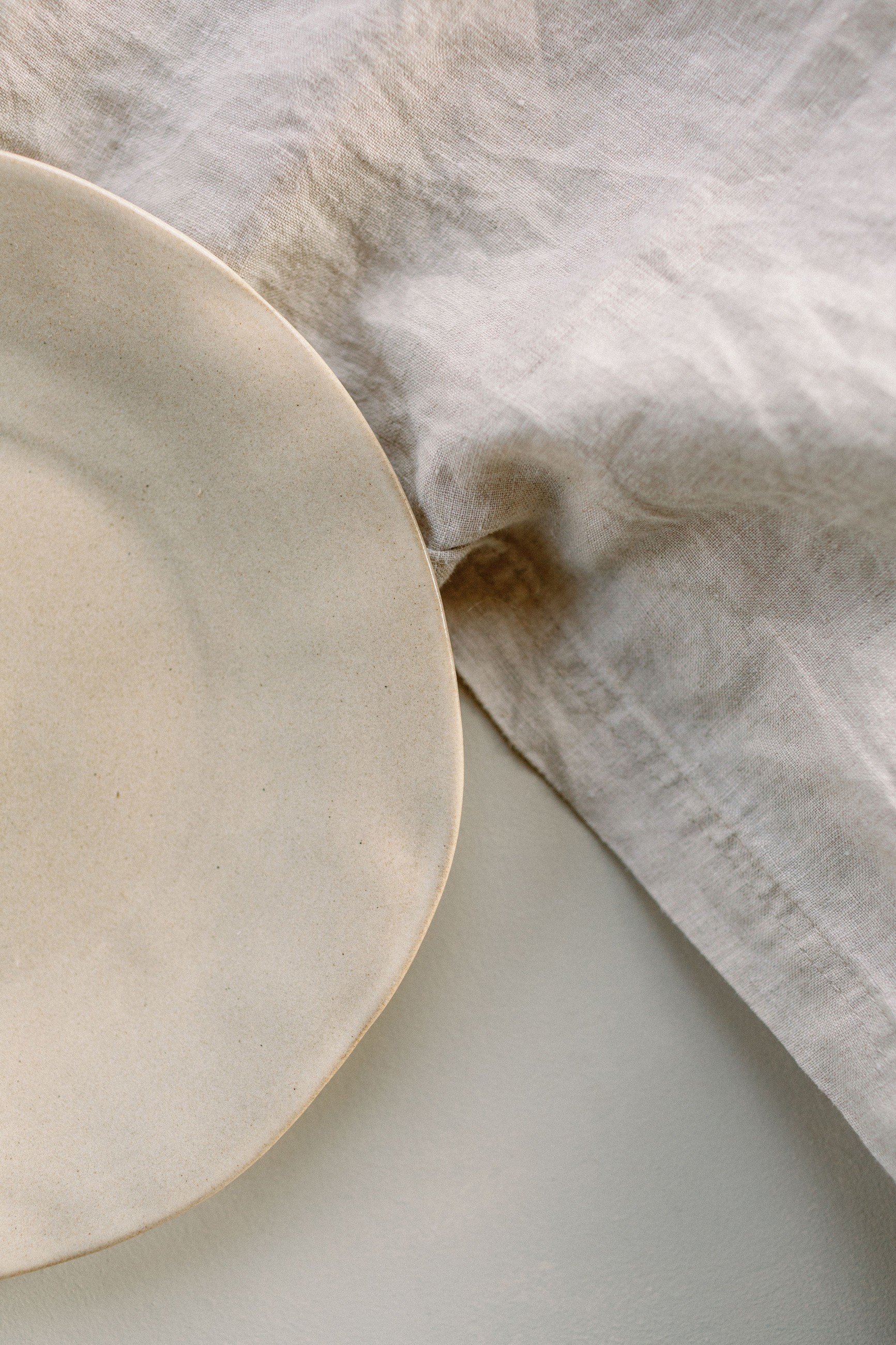 Ceramic plate resting on natural linen — the quiet, tactile world of Lado