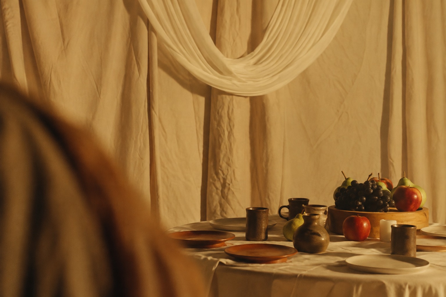 Family-style table set with candles, fruit, and draped linen