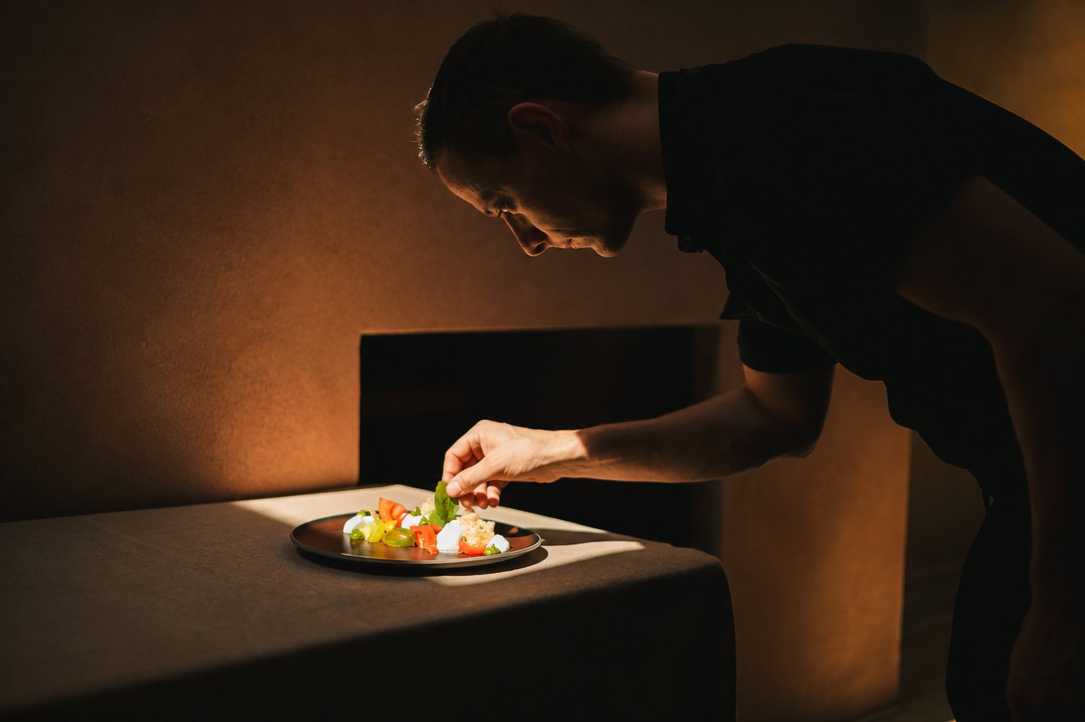 Chef plating a dish in warm evening light