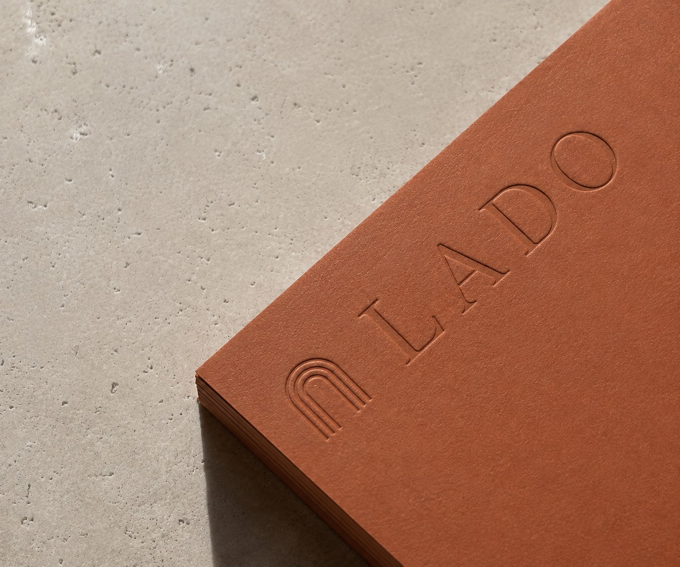 LADO wordmark embossed on a terracotta notebook