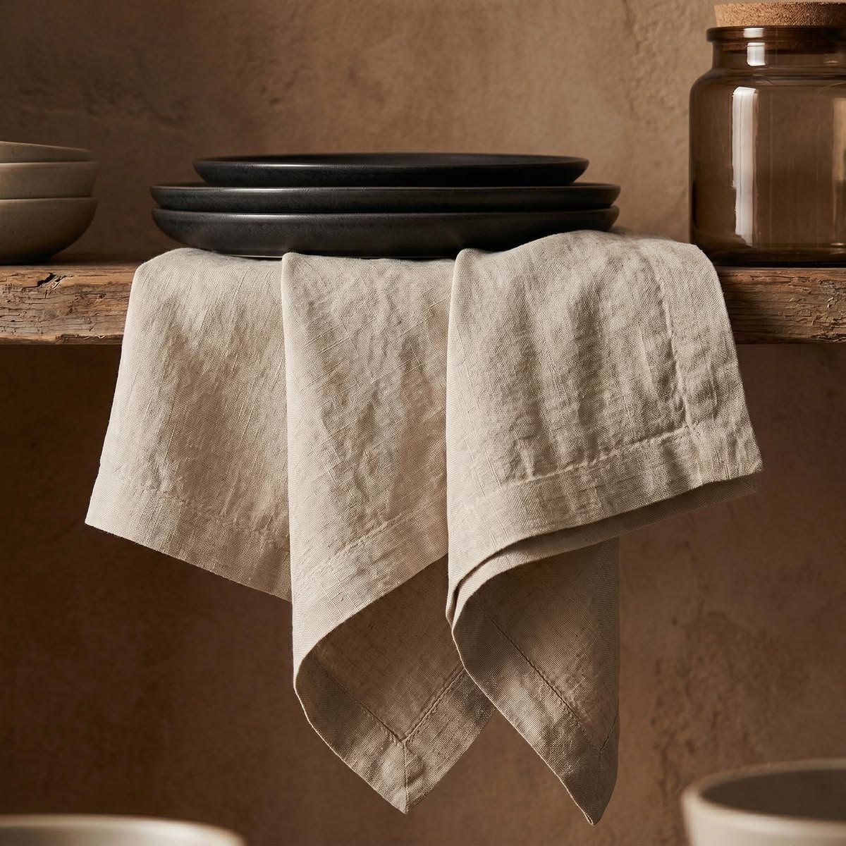 Stacked ceramic plates and linen on a terracotta shelf