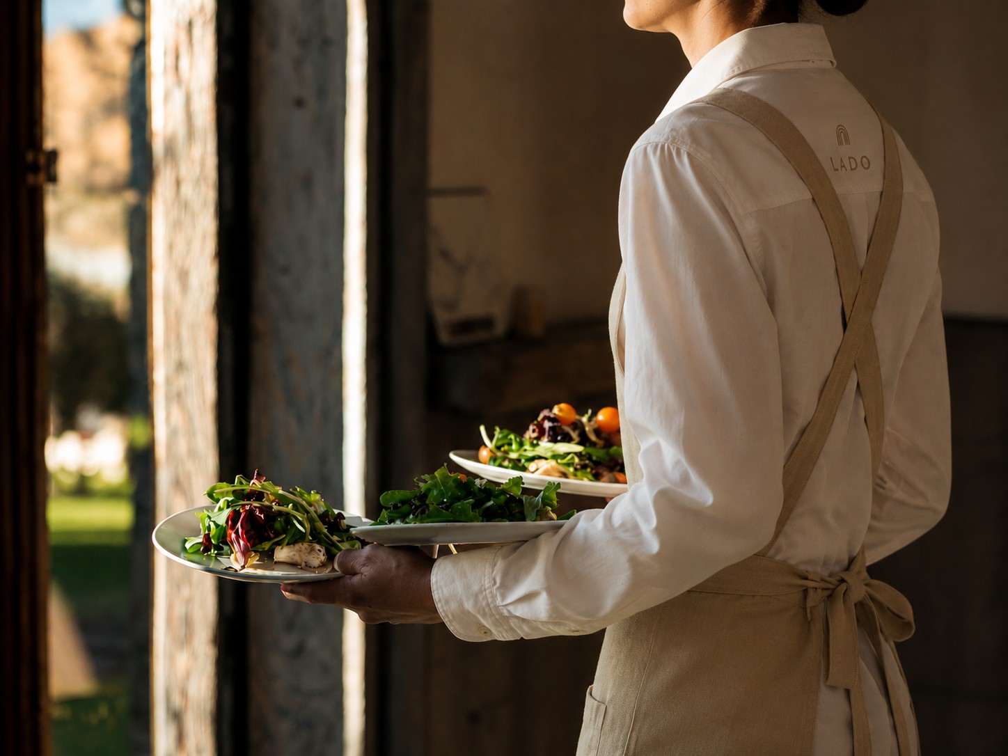 Lado server carrying plated dishes through a doorway